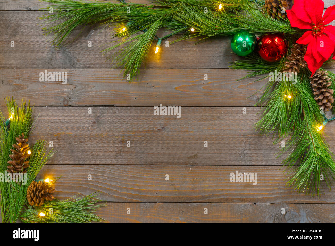 Christmas background with spruce greens, ornaments and lights on weathered pine boards Stock Photo