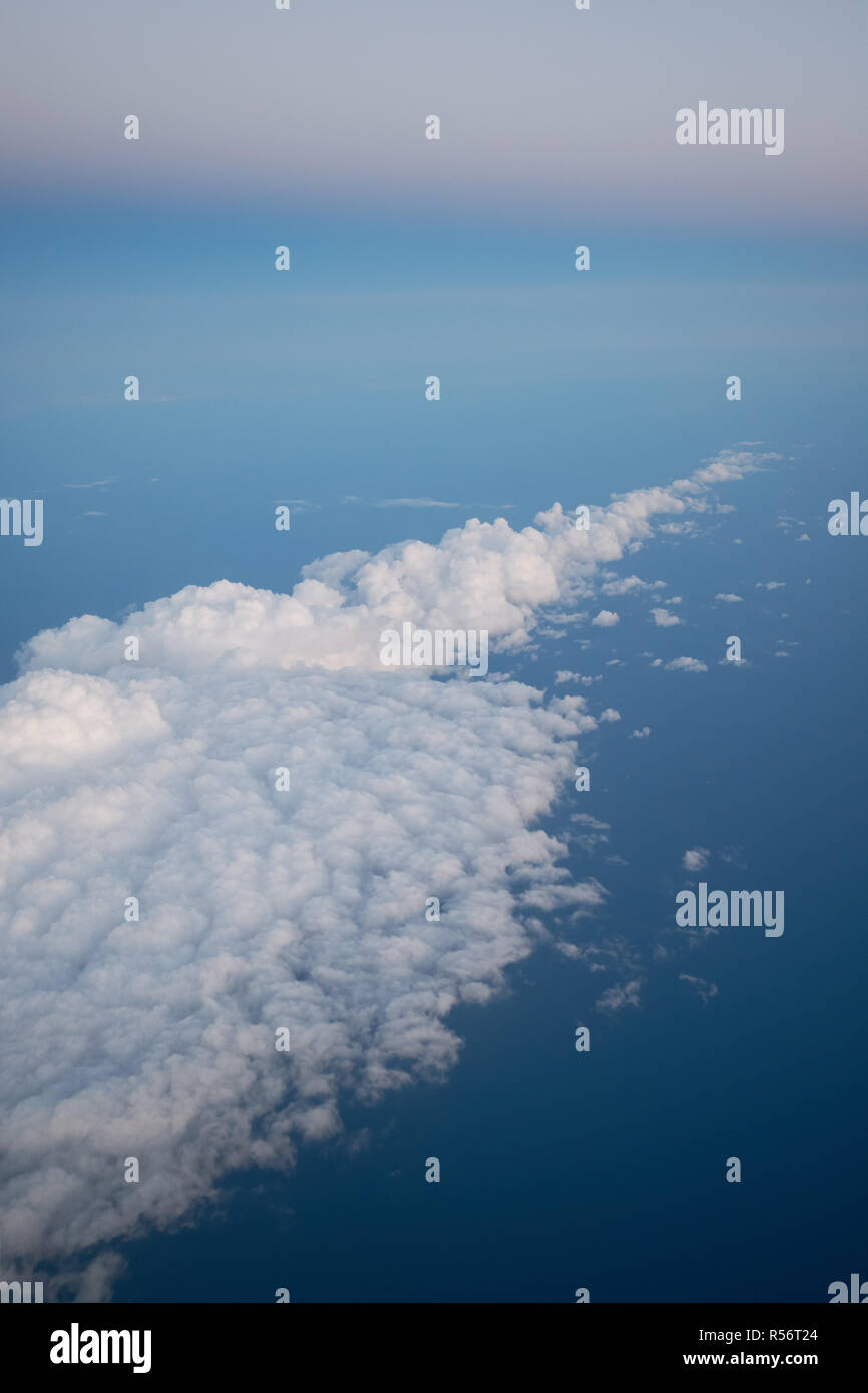 Sunrise above fluffy white clouds and blue Mediterranean Sea, view from airplane window. Flight over Spain Stock Photo