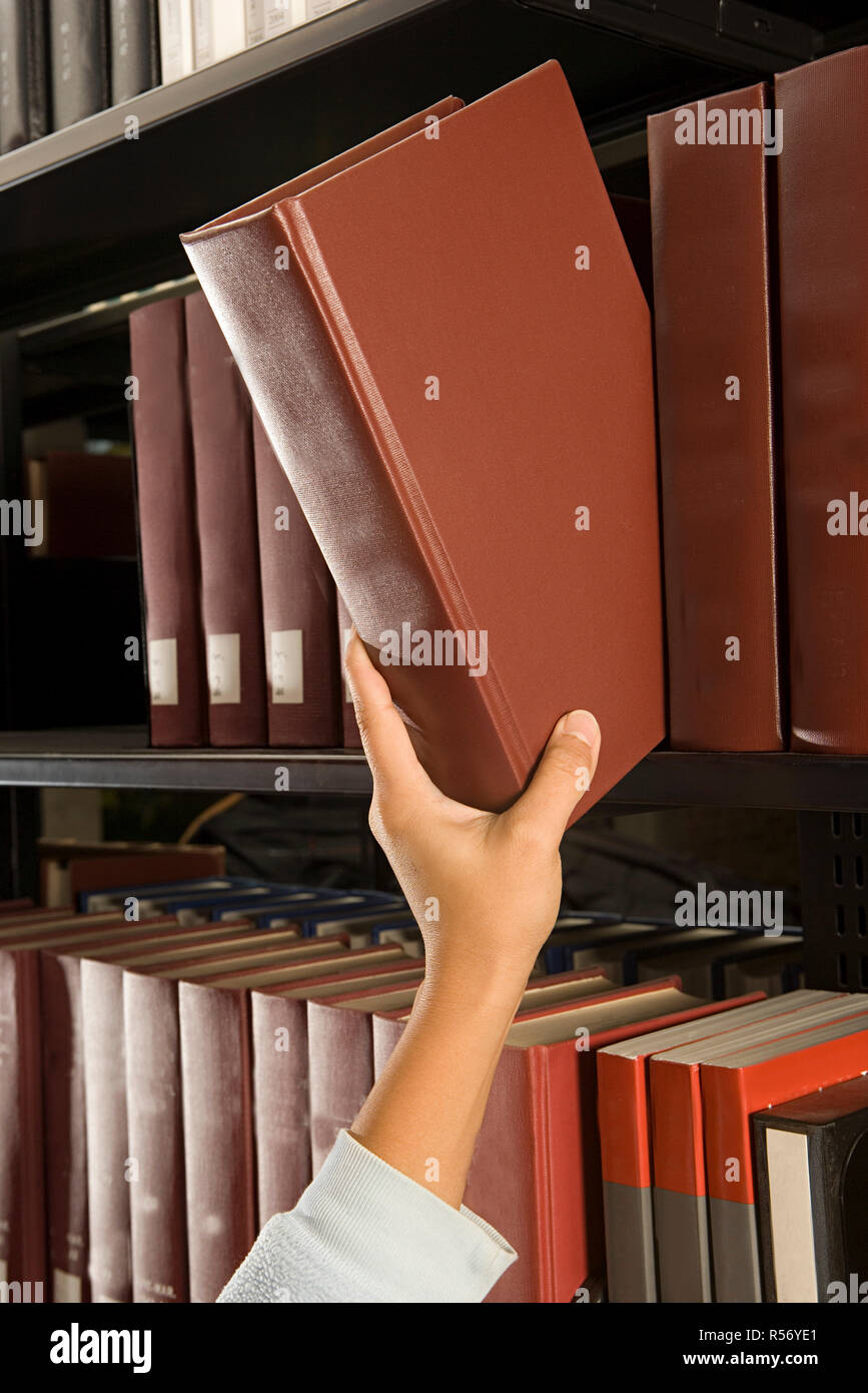 Female student reaching for a book Stock Photo