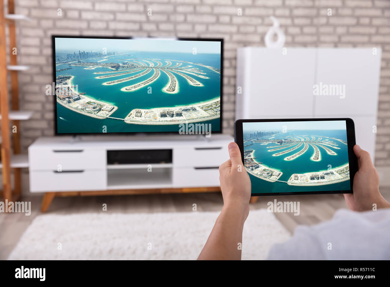 Man Holding Digital Tablet In Front Of Television Streaming Movie Stock Photo