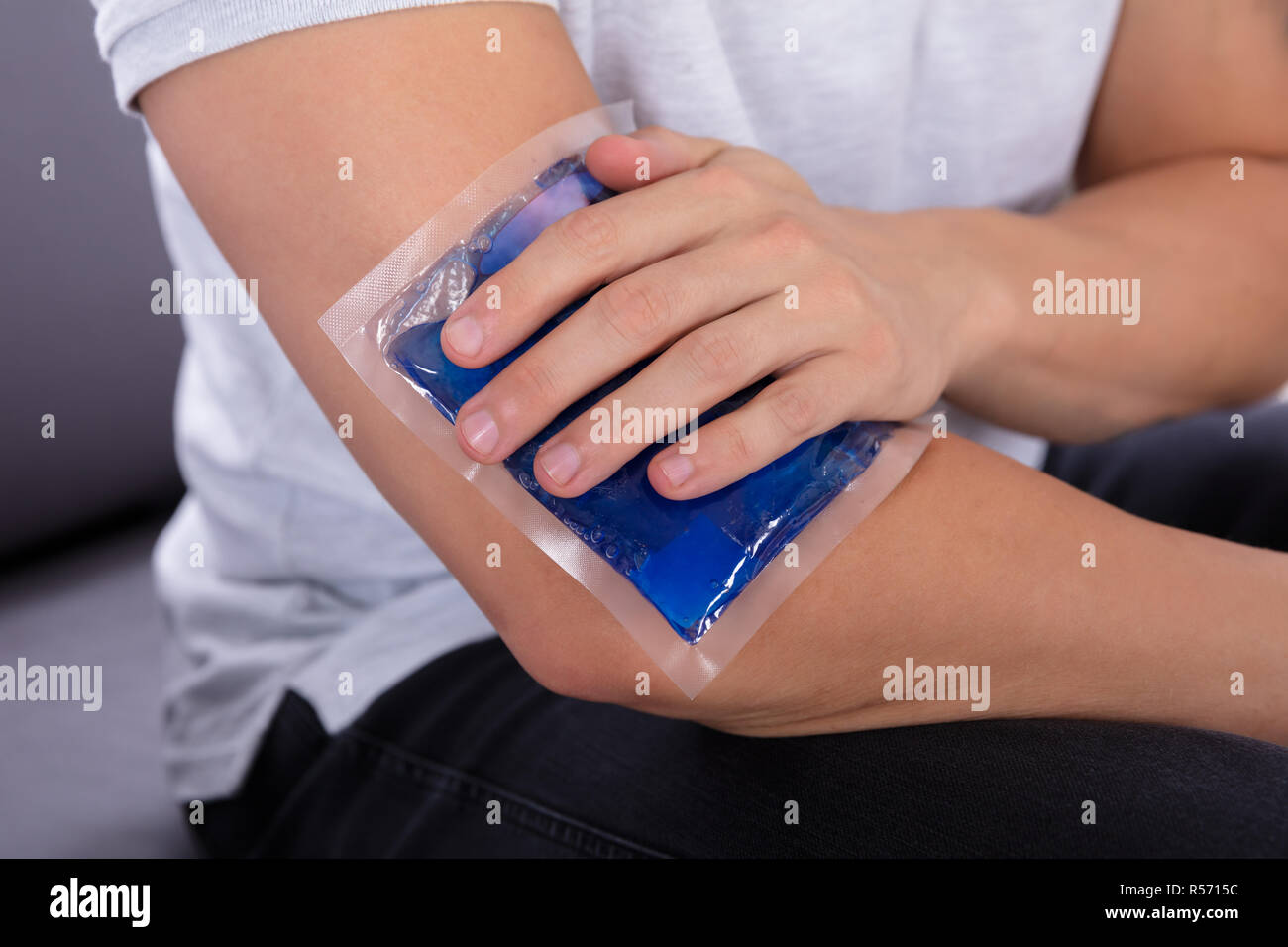 Closeup Of A Man's Hand Applying Ice Gel Pack On An Injured Elbow