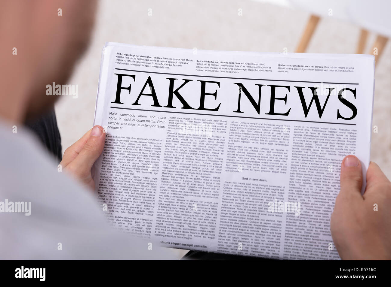 Close-up Of A Man's Hand Holding Newspaper With Fake News Stock Photo