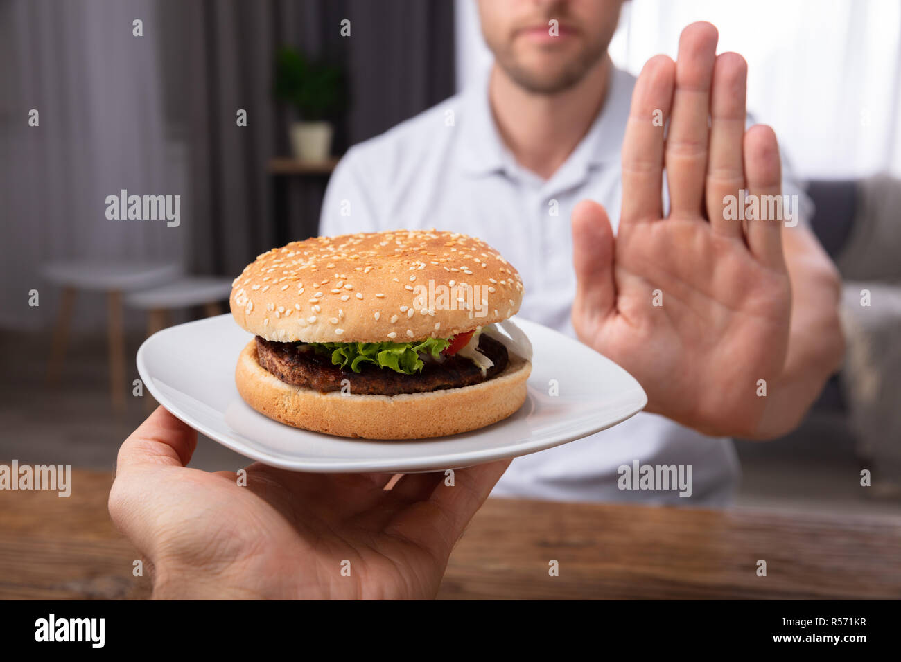 Close-up Of A Man's Hand Refusing Burger Offered By Person Stock Photo