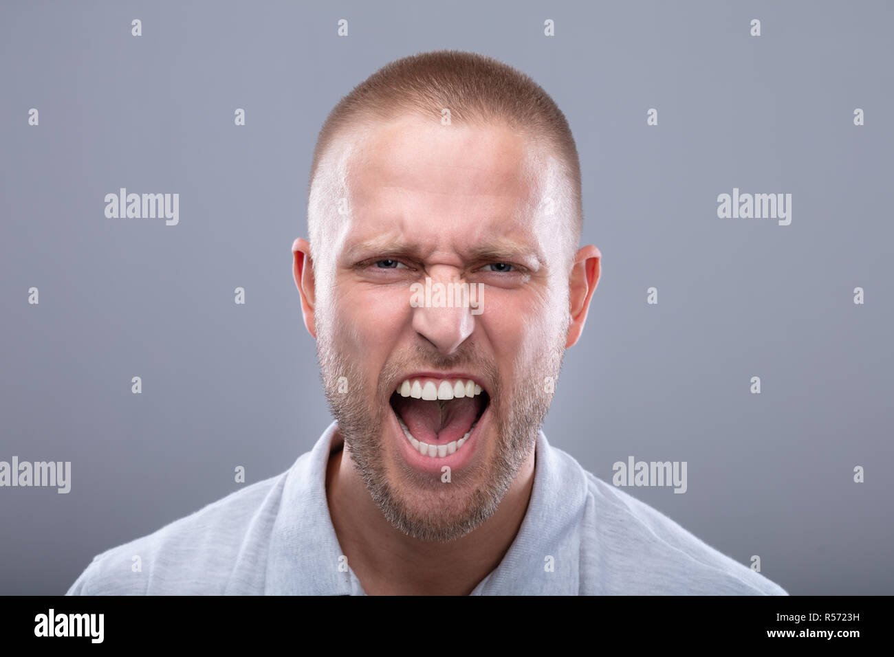Portrait Of A Shouting Young Man On Grey Background Stock Photo