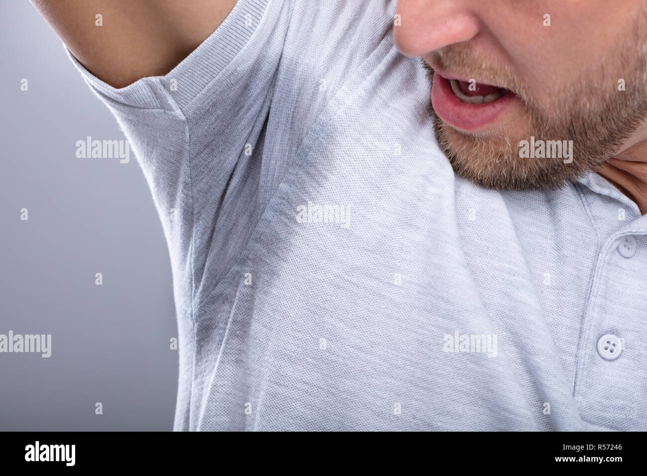Close-up Of A Man In Grey T-shirt Looking At His Sweaty Armpit Stock Photo