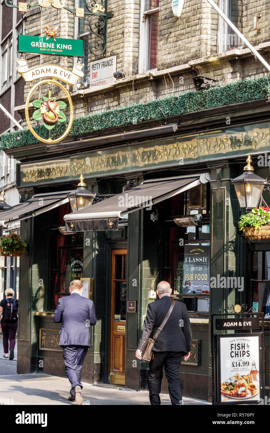 London England,UK,Westminster,Adam & Eve 18th century pub,traditional public house,bar lounge pub,exterior,Greene King sign,businessman,pedestrian,UK Stock Photo