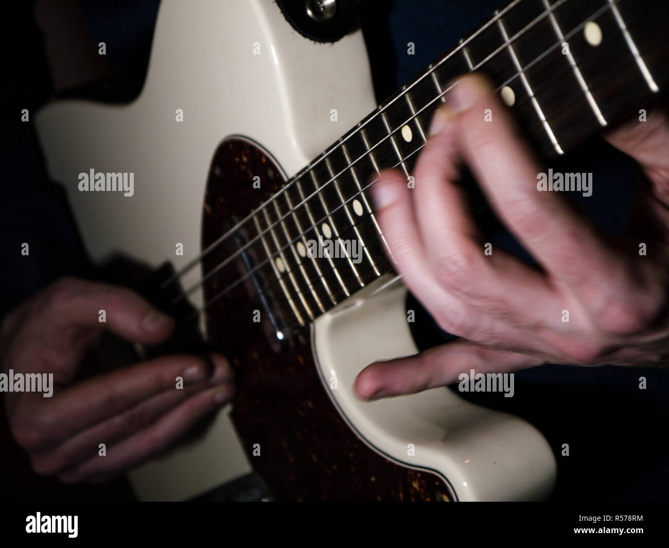 Close-up shot of a guitarist playing on an electric guitar, with motion blur of the hands Stock Photo