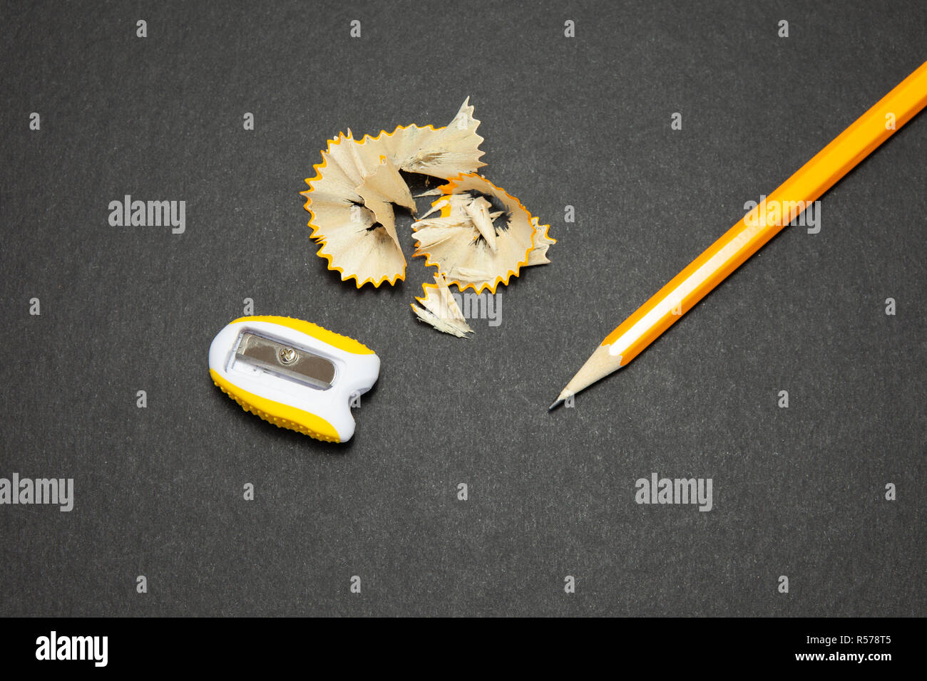 Sharpened pencil and sharpener on black background. Stock Photo