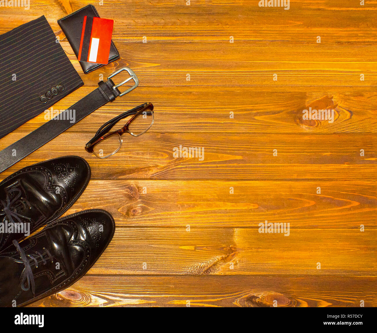 The elegant male set: men's shoes, leather belt, on the wooden background. Stock Photo
