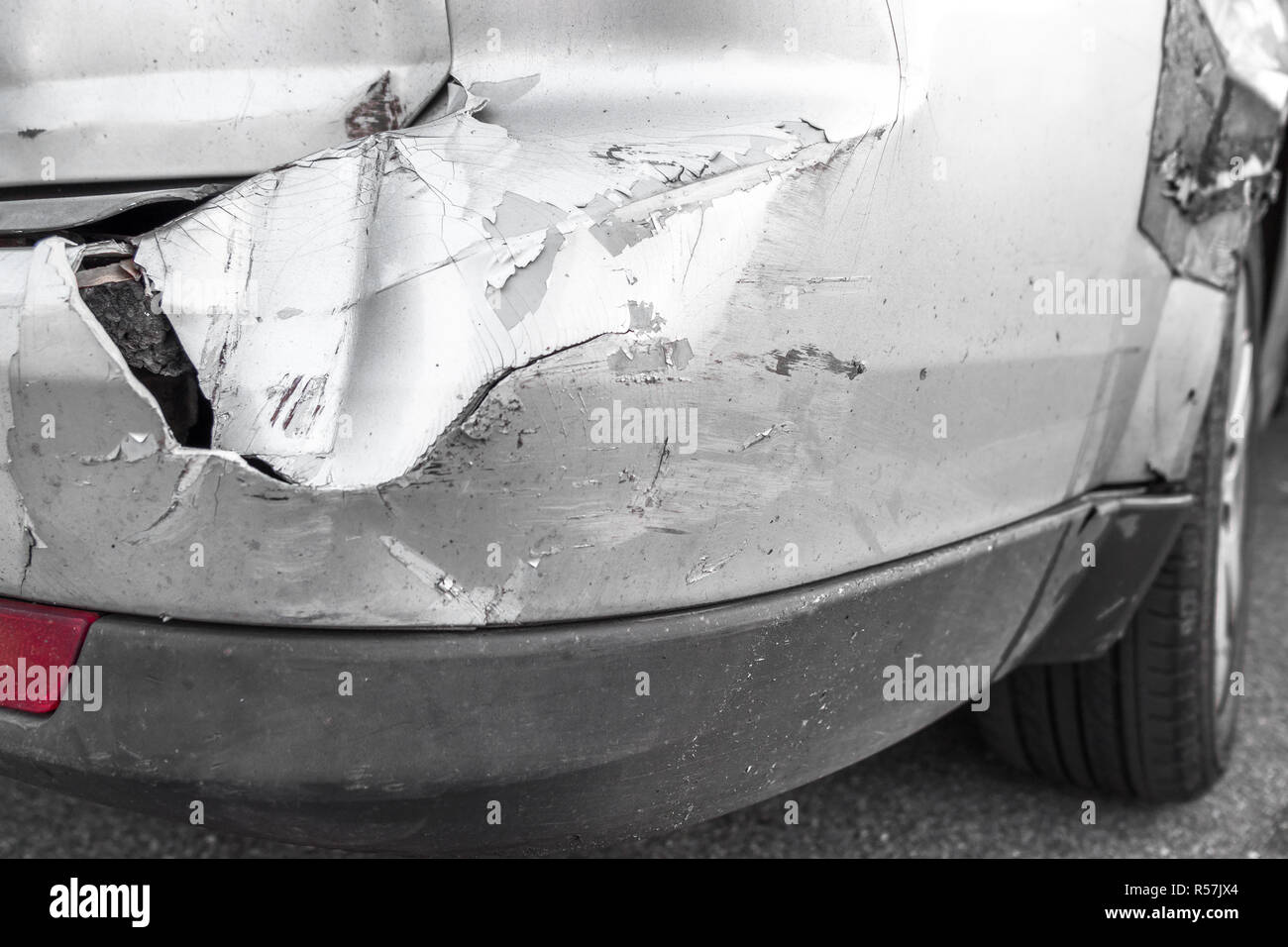 Silver car with rear part damaged in crash accident or collision with scratched paint and dented rear bumper metal body. Stock Photo