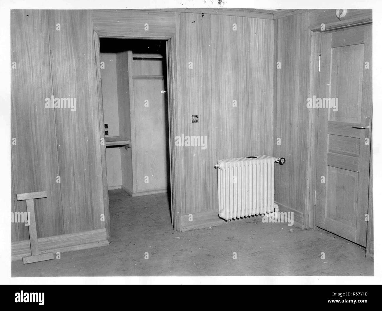 Original Caption: Interior of a bunker cabin looking from the living room into the sleeping compartment. Note the wall paneling, steam heat radiator, light switches; and just over the built in table visible through the doorway are wall plugs for radio and telephones, in an abandoned installation in the hills northwest of Soissons, France. Stock Photo