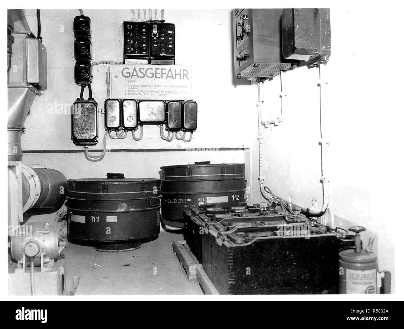 Original Caption: An abandoned German installation in the hills northwest of Soissons, shows the air conditioning and gas filtering unit inside the air raid bunkers. Intake and outlet pipes are on the left. Spare filter units are shown lower center, below the switchboard and fuse boxes. On wall to right is master control box, above row of batteries for emergency power. Stock Photo