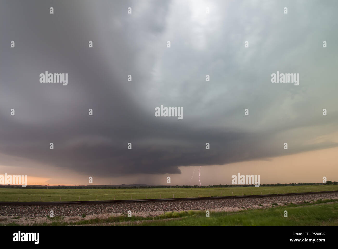 Supercell thunderstorm with lightning strike near sunset Stock Photo ...