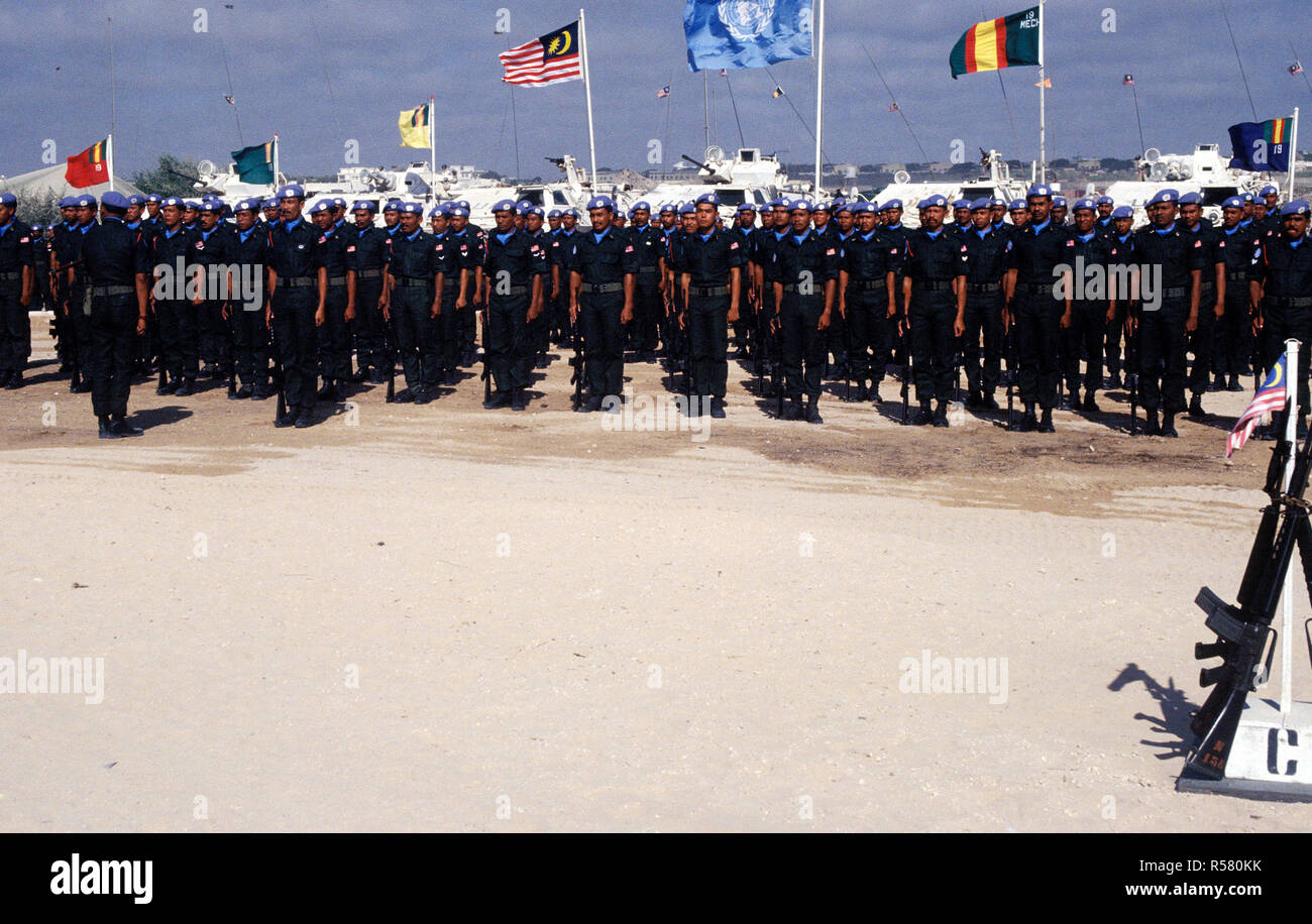 1993 - Malaysian Army troops stand at attention during their awards ceremony held at the Mogadishu airport.  The United Nations and Malaysian flags are visible in the background. Stock Photo