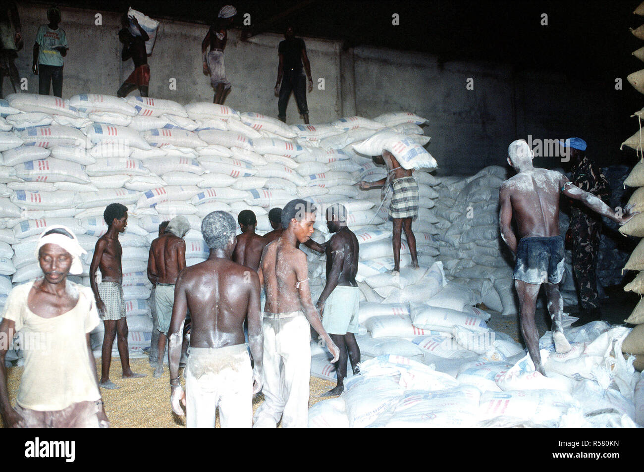1993 - Somali men work in a food storage warehouse in Kismayo. The supplies are deliverd to food distribution centers by a Belgian contingent that is in Somalia in support of OPERATION CONTINUE HOPE. Stock Photo