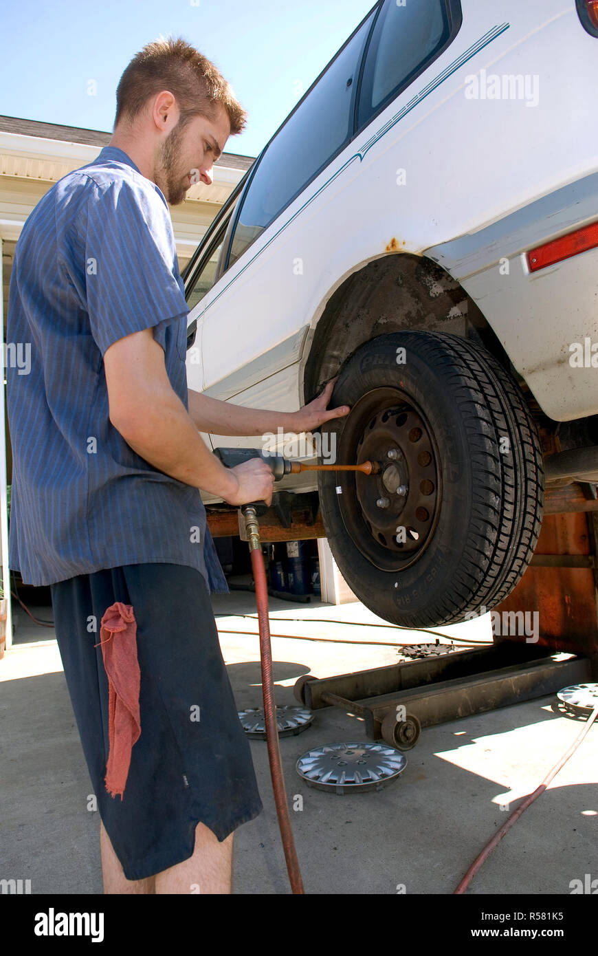 2007 - Mechanic removing lugnuts from the wheel of a car on a lift Stock Photo