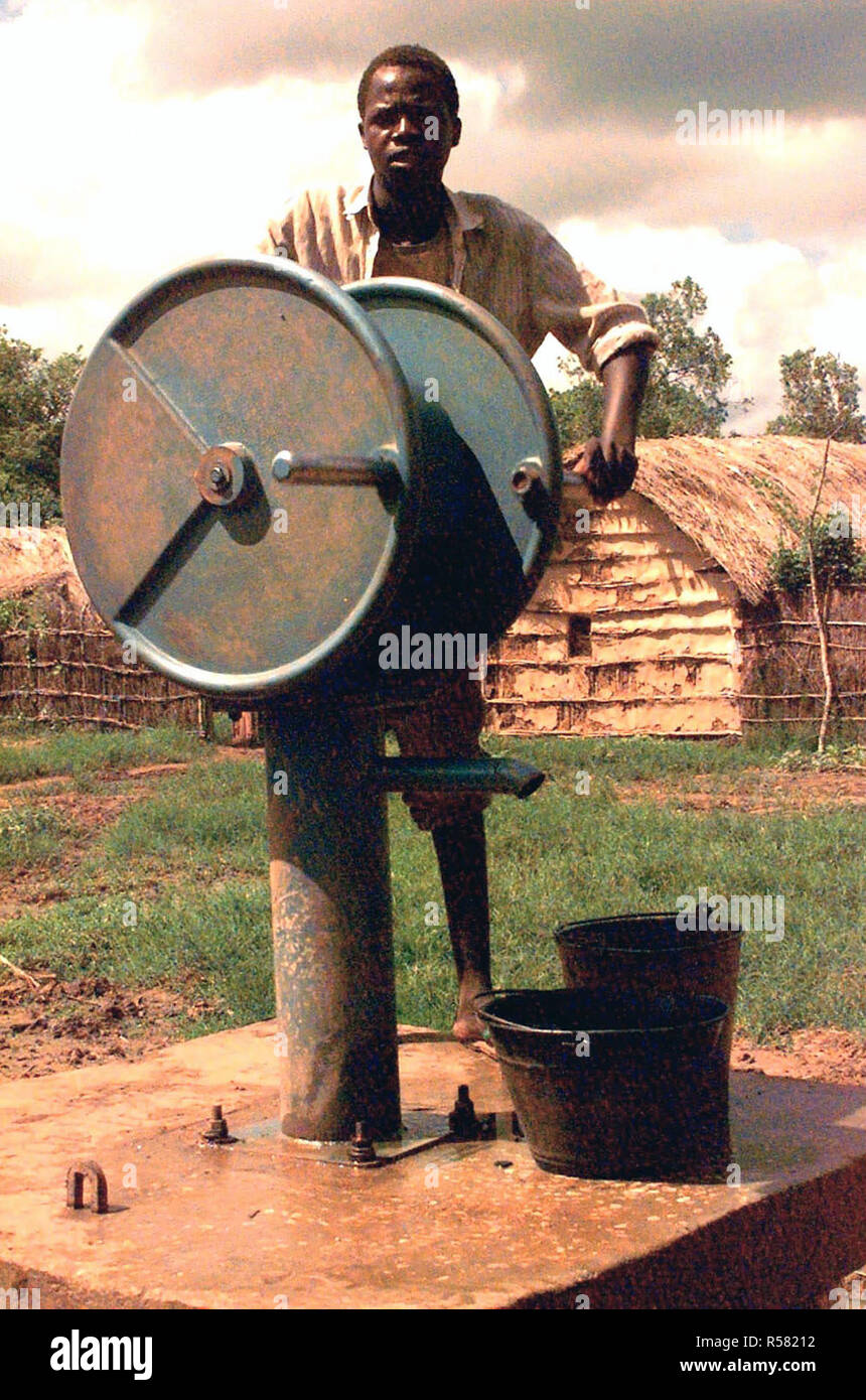 1993 - Straight of shot of a Somali boy standing behind a large wheel that acts as a pump to a water well in the village of Mogambo, Somalia.  Belgian engineers (not shown) deployed to Kismayo, Somalia in support of Operation Continue Hope dug the new well and installed the pump to replenish the diminishing water supply of the village. Stock Photo