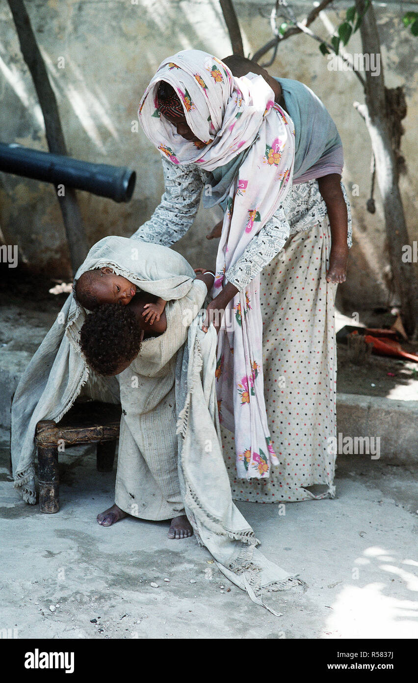 1993 - A Somali woman helps her daughter secure an infant to her back during the multinational relief effort Operation Restore Hope. Stock Photo