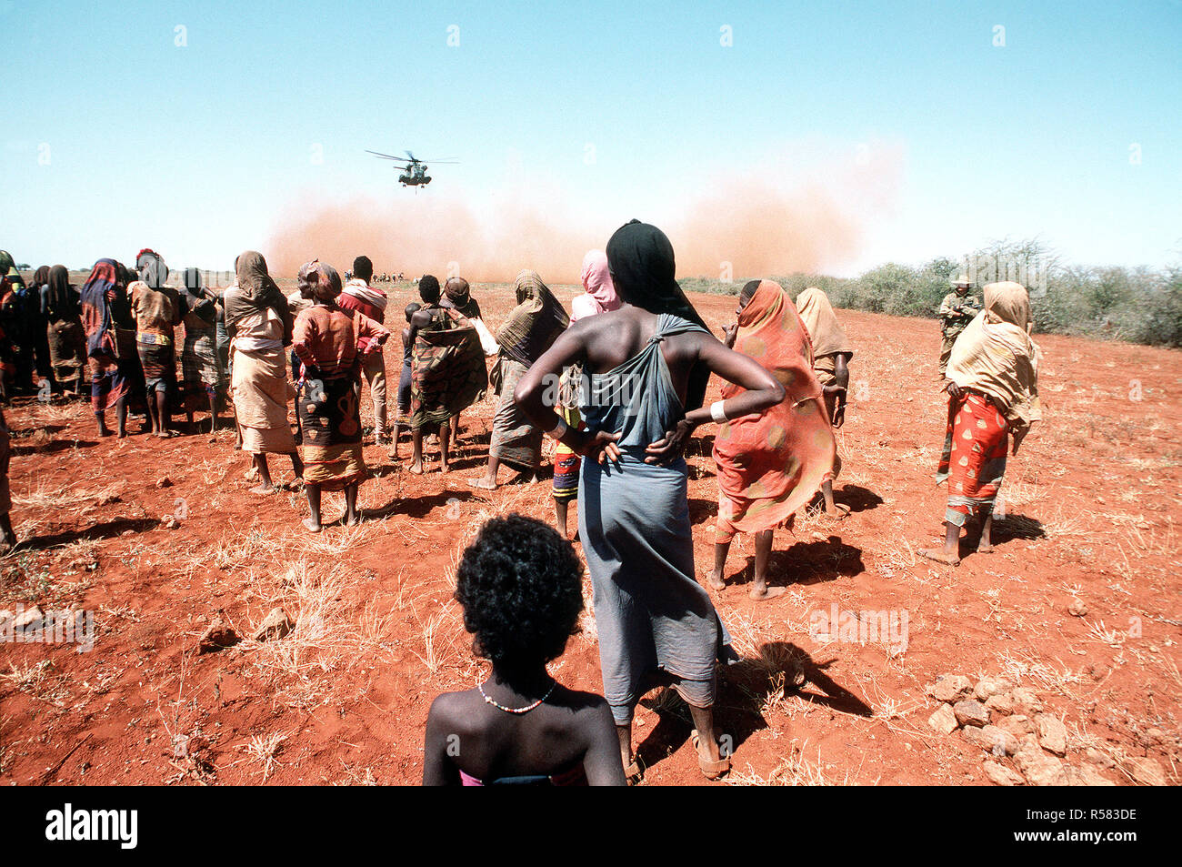 1993 - Villagers watch as a Marine Heavy Helicopter Squadron 363 (HMH-363) CH-53D Sea Stallion helicopter lifts off after delivering a load of grain during the multinational relief effort OPERATION RESTORE HOPE. Stock Photo