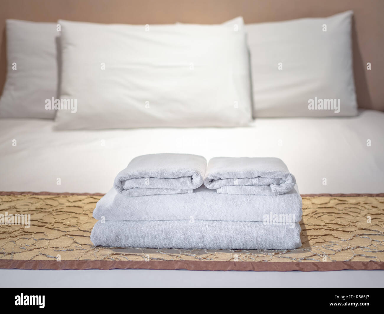 Clean white towels and three white pillows on bed in luxury room in