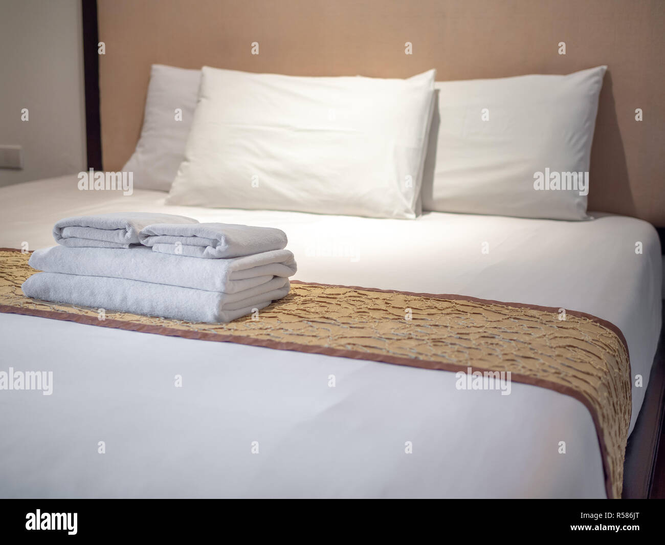 Clean white towels and three white pillows on bed in luxury room in