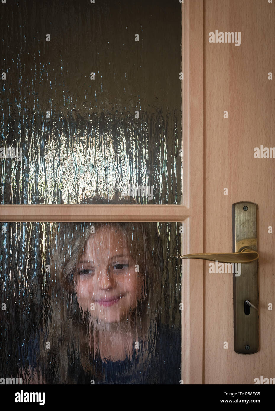 Portrait of a cute little Caucasian girl hiding behind a door with