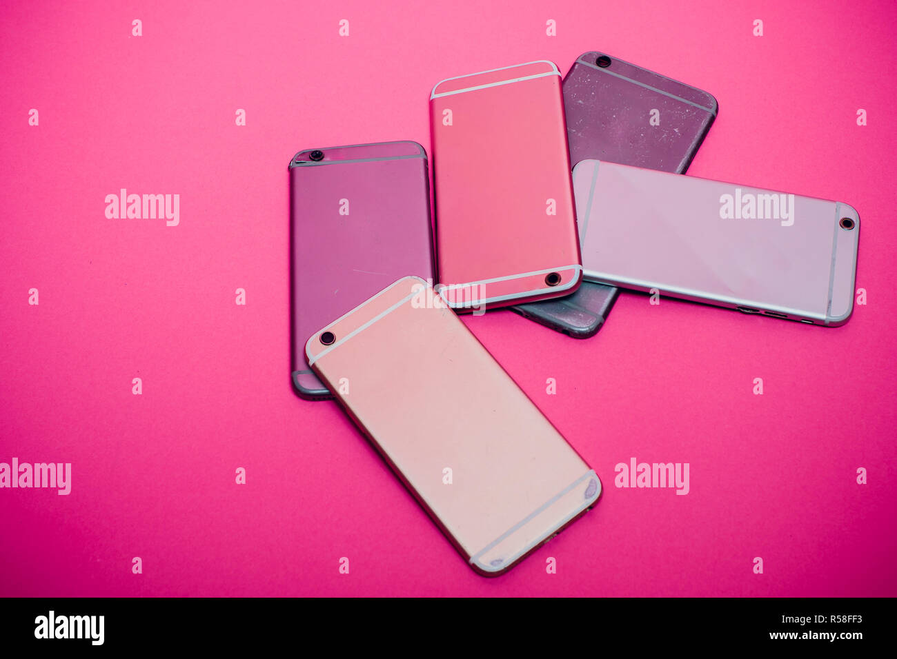Broken mobile phone lies on a pink background. Stock Photo