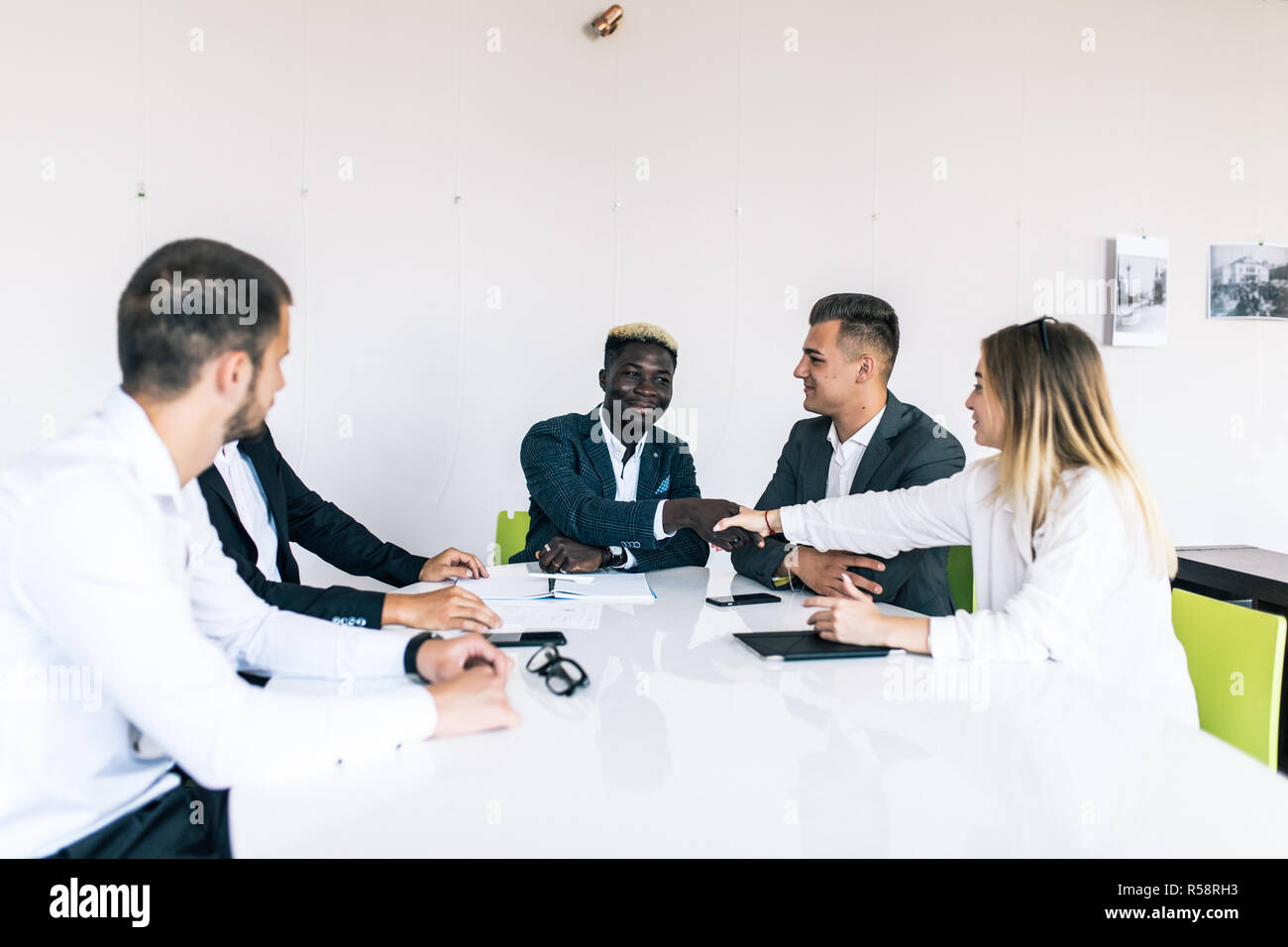 A confident business team of mixed ages and ethnicity making handshaking while meeting in a modern office. They are discussing ideas for their busines Stock Photo