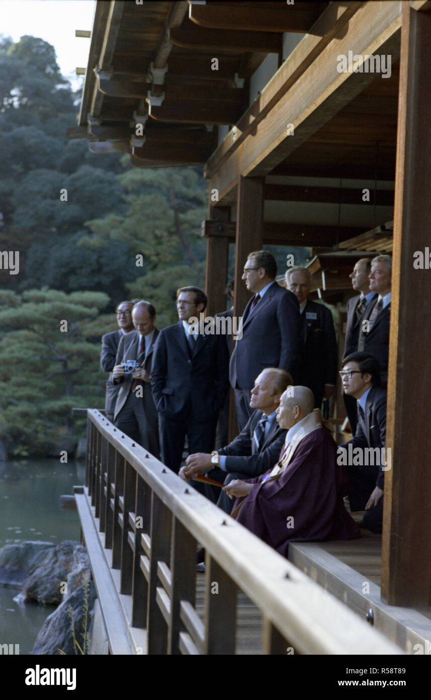 1974, November 21 – Kinkakuji Castle (Gold Pavilion) – Kyoto, Japan – Gerald R. Ford, Zen Buddhist Abbot Jikai Murakami, Interpreter, Secretary of State Henry A. Kissinger,  Donald Rumsfeld; Other Members of US and Japanese Travelling Group – An interpreter sits between President Ford and Zen Buddhist Abbot Jikai Murakami as the two chat in the pavilion above the Cyoko Chi Pond - First Visit to Japan by a Sitting US President - Tour of  Zen Buddhist Shrine - Abbott of Gold Pavilion Stock Photo