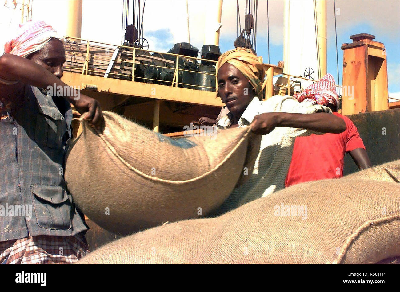 1993 - Somali workers unload a ship carrying sacks of wheat donated by the European communities on the port of Mogadishu, Somalia.  This mission is in support of Operation Restore Hope. Stock Photo