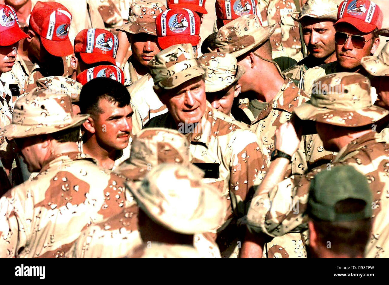1993 - US President George Bush is centered in the frame, facing the camera and surrounded by several members of the US Forces assigned to the mission in Somalia.  Those wearing red hats belong to the Air Force RedHorse team from Hurlburt Field, Florida.  The President visited Somalia to show is gratitude to those involved in the mission of Operation Restore Hope. Stock Photo