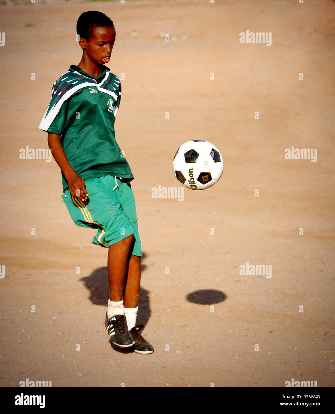 A boy from the Djibouti City's Boy's Orphanage kicks a soccer ball donated by U.S. Military Service Members deployed with Combined Joint Task Force - Horn of Africa (CJTF-HOA).  - Horn of Africa is a unit of U.S. Central Command that conducts operations and training to assist Partner nations to combat terrorism in order to establish a secure environment and enable regional stability. Stock Photo