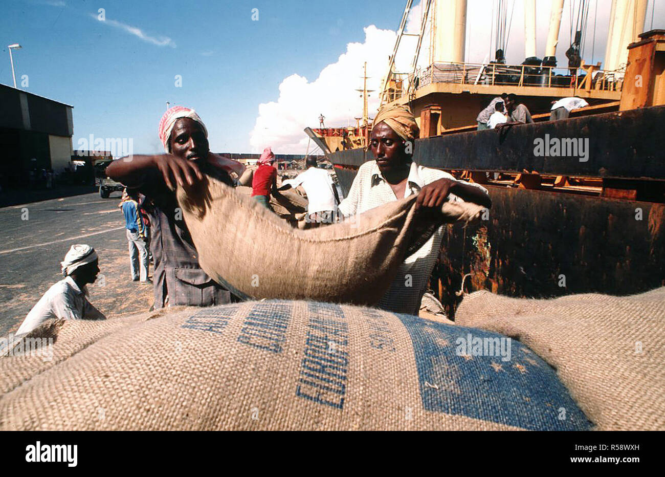 1993 - Somali dock workers carry sacks of wheat in the port as they unload relief supplies for their country. (Mogadishu Somalia) Stock Photo