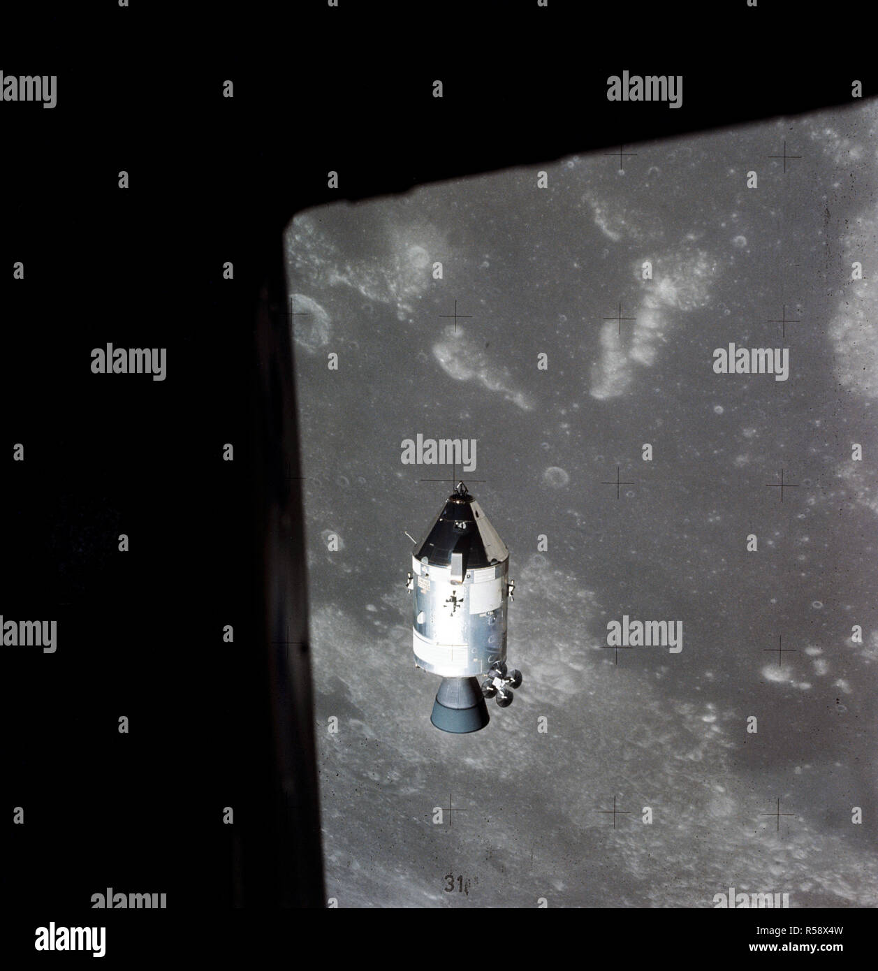 (30 July 1971) --- A view of the Apollo 15 Command and Service Modules (CSM) in lunar orbit as photographed from the Lunar Module (LM) just after rendezvous. The lunar nearside is in the background. This view is looking southeast into the Sea of Fertility. The crater Taruntius is at the right center edge of the picture. Stock Photo