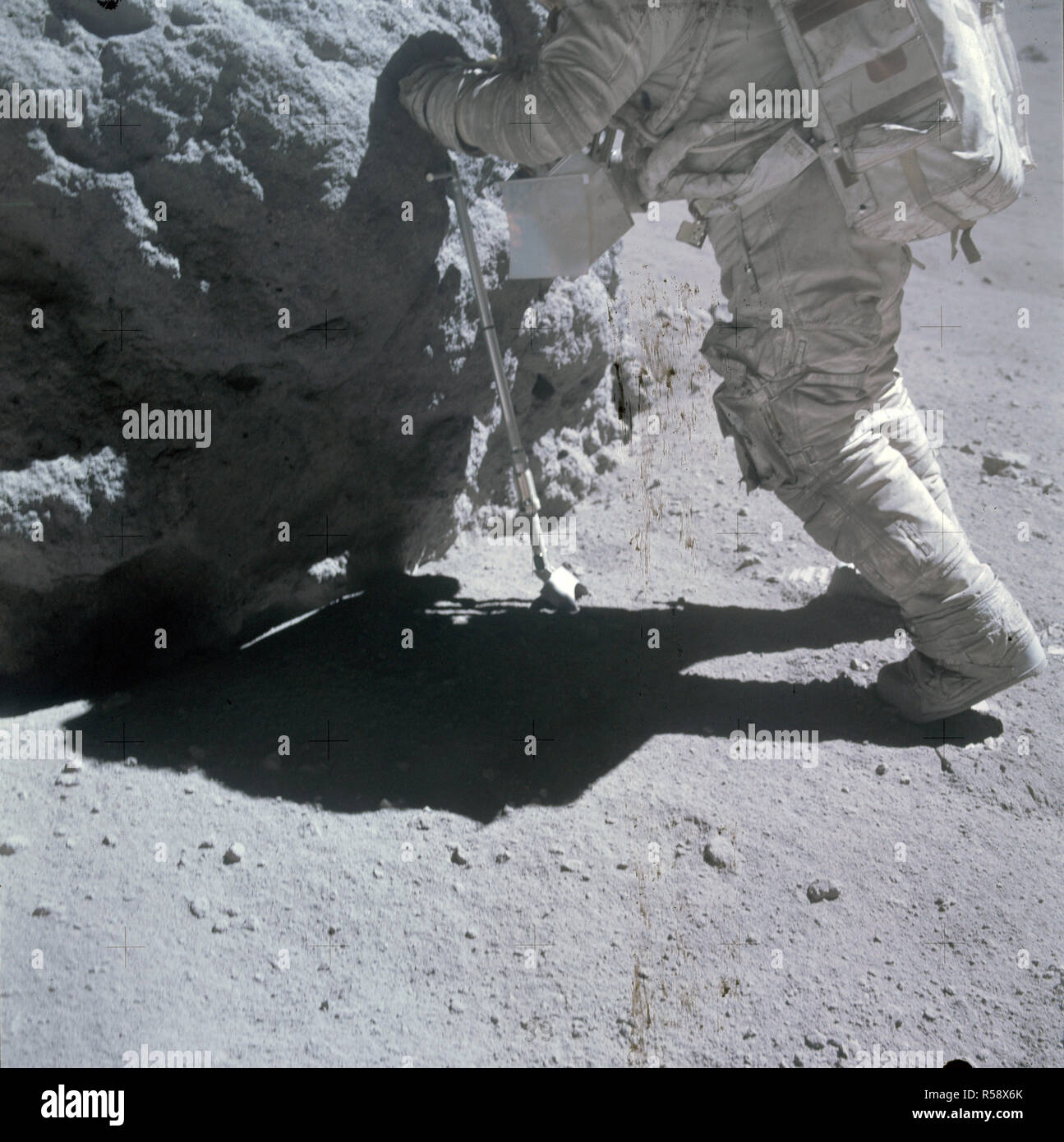 (23 April 1972) --- Astronaut Charles M. Duke Jr., lunar module pilot, works at the 'Shadow Rock', discovered during the missions third extravehicular activity (EVA) in the area of North Ray Crater (Station 13), April 23, 1972. The scoop, a geological hand tool, leans against the rock. Stock Photo