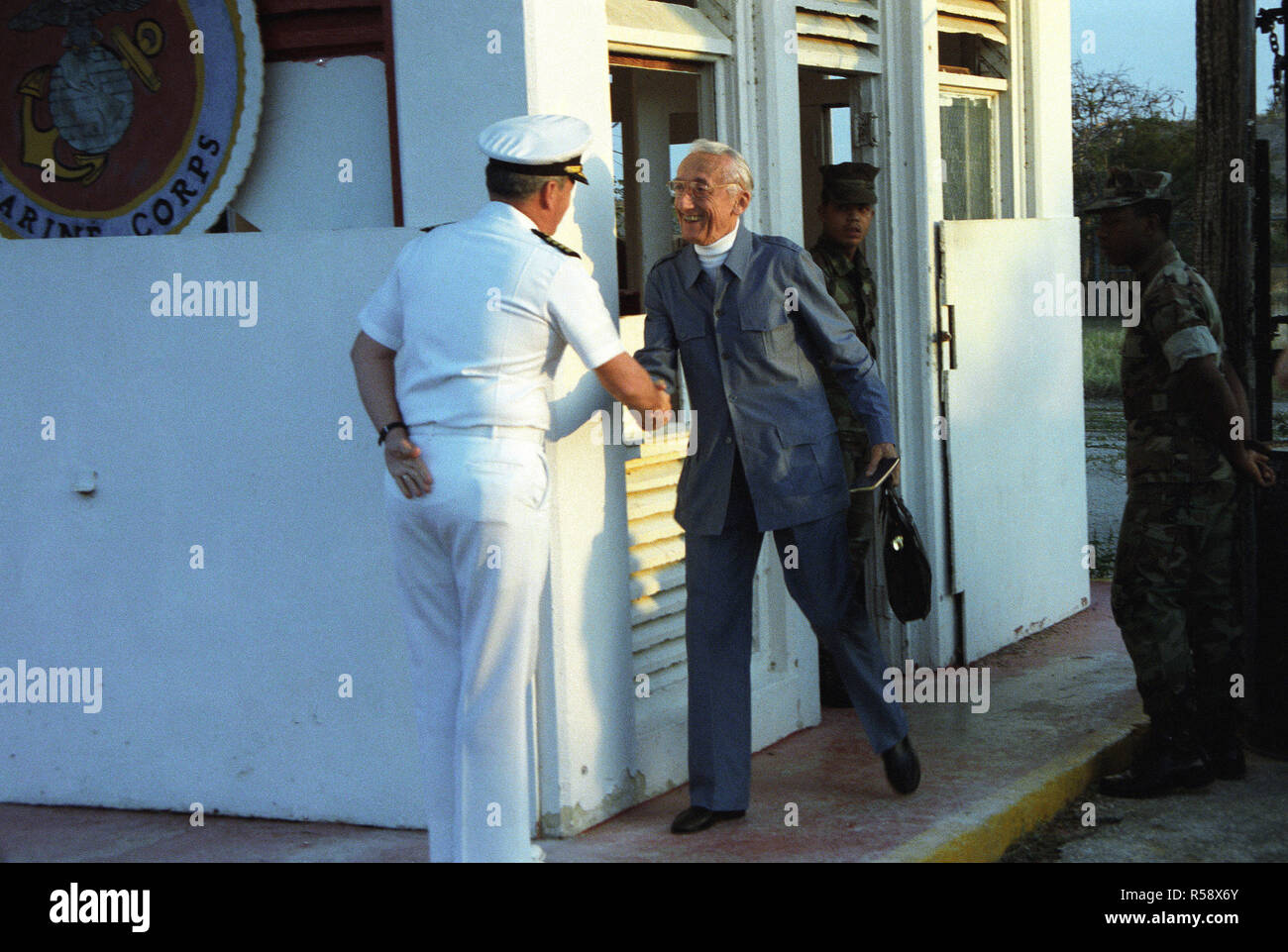 Explorer Jacques Cousteau is greeted by a US Navy officer after passing through the northeast gate separating communist Cuba and the US naval base.  Cousteau is studying the ecology in the waters surrounding the island. Stock Photo