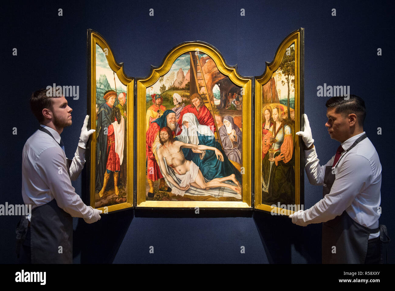 Christie's art handlers with a triptych painting from the Antwerp School, dated circa 1500-1550, valued at &pound;250,000 - &pound;350,000, on show at Christie's saleroom in central London ahead of the auction house's forthcoming Classic Week sales. Stock Photo