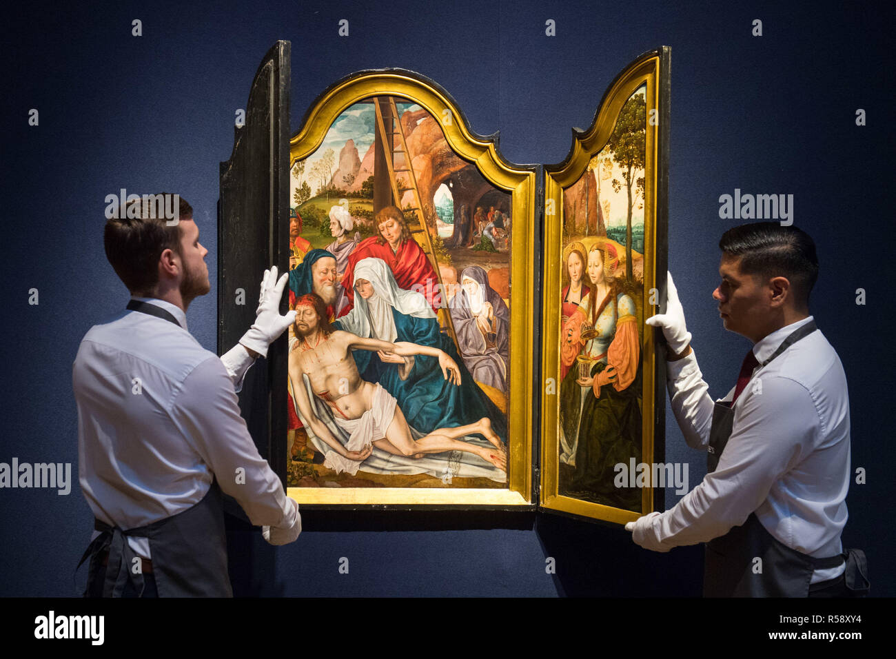 Christie's art handlers with a triptych painting from the Antwerp School, dated circa 1500-1550, valued at £250,000 - £350,000, on show at Christie's saleroom in central London ahead of the auction house's forthcoming Classic Week sales. Stock Photo