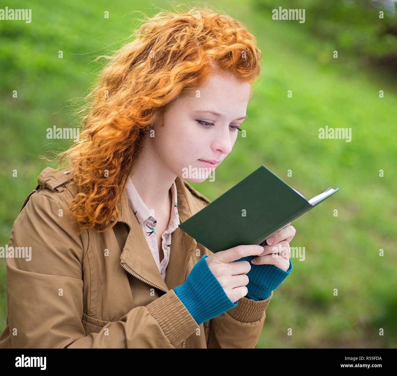 Young beautiful woman in park reading a book. Stock Photo