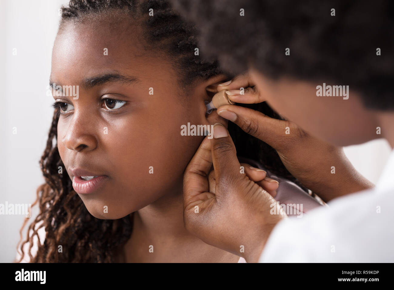 Doctor Putting Hearing Aid In Patient's Ear Stock Photo