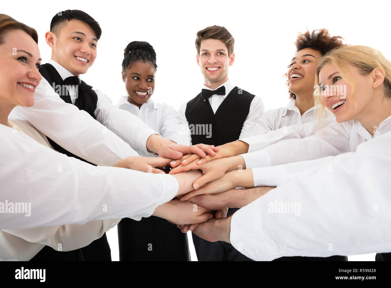 Smiling Young Restaurant Staff Stacking Hands Stock Photo