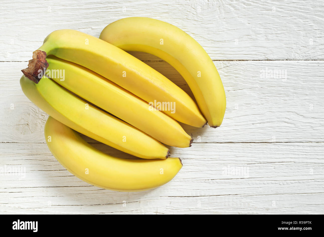 Bunch of yellow bananas on a white wooden background, top view with ...