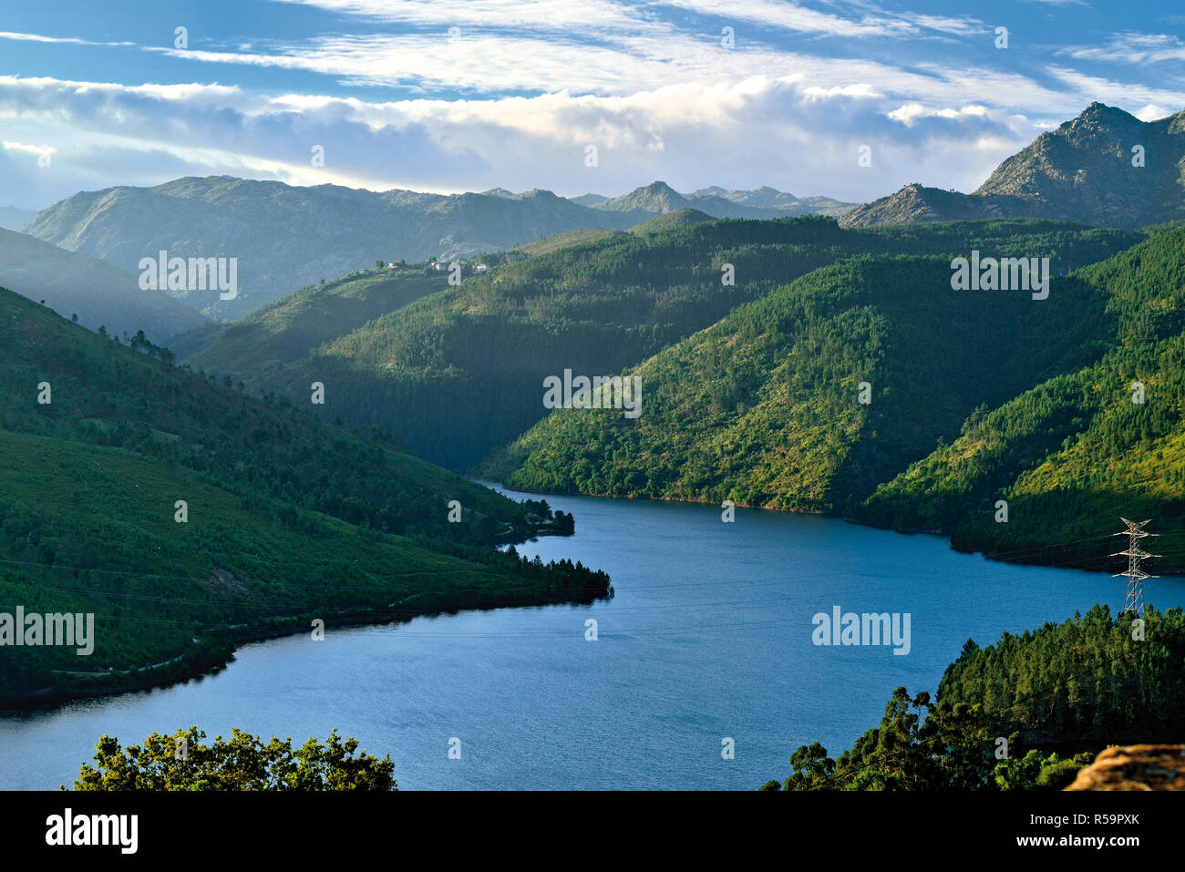 View to idyllic lake surrounded by green mountains with dramatic cloudy sky Stock Photo