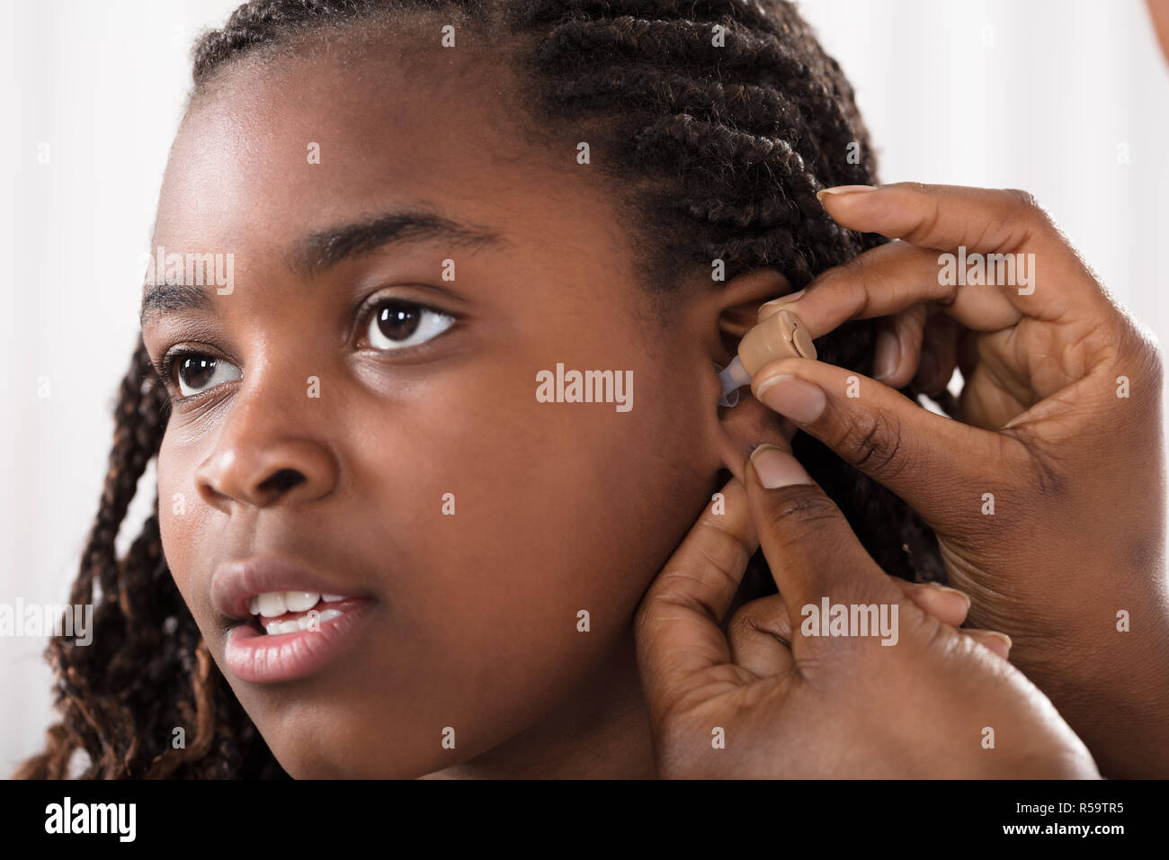 Doctor Putting Hearing Aid In Patient's Ear Stock Photo