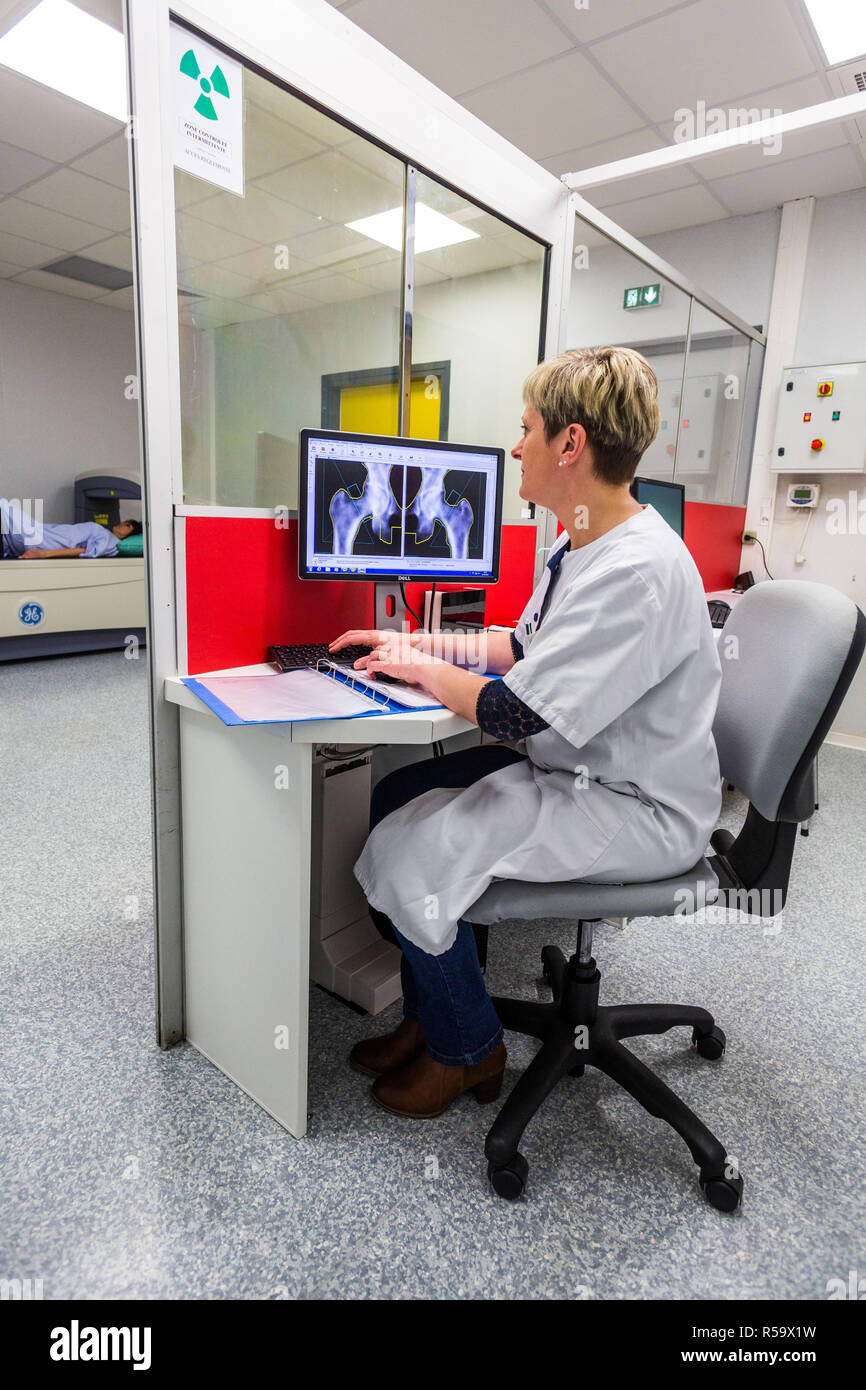 A doctor uses a bone densitometer to measure the optical density of the neck of the femur of female patient to diagnose osteoporosis, Angouleme hospit Stock Photo