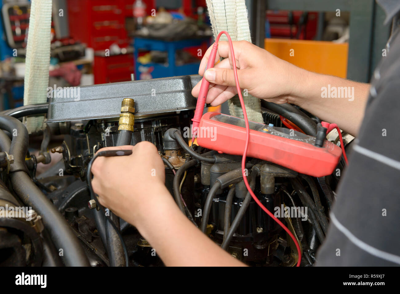 mechanic man with digital multimeter testing ignition coil Stock Photo