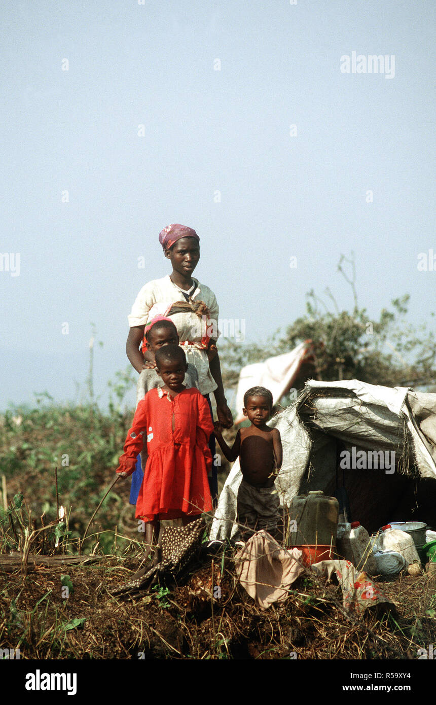 1994 - Rwandan refugee family of mother and children stand by a makeshift shelter, which along with what they carry, constitute all their worldly possessions.  They are in the Kibuma refugee camp near Goma Zaire after a civil war erupted in their country. Stock Photo