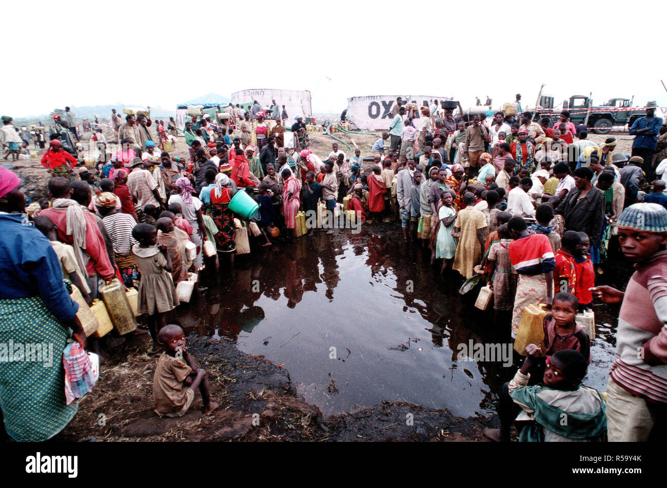 1994 Zaire- Refugees from Rwanda's bitter civil war between the Hutus and Tutsis tribes in Southern Africa, gather with anything that will hold water, to get much needed food and water, supplied by US military relief efforts. Stock Photo