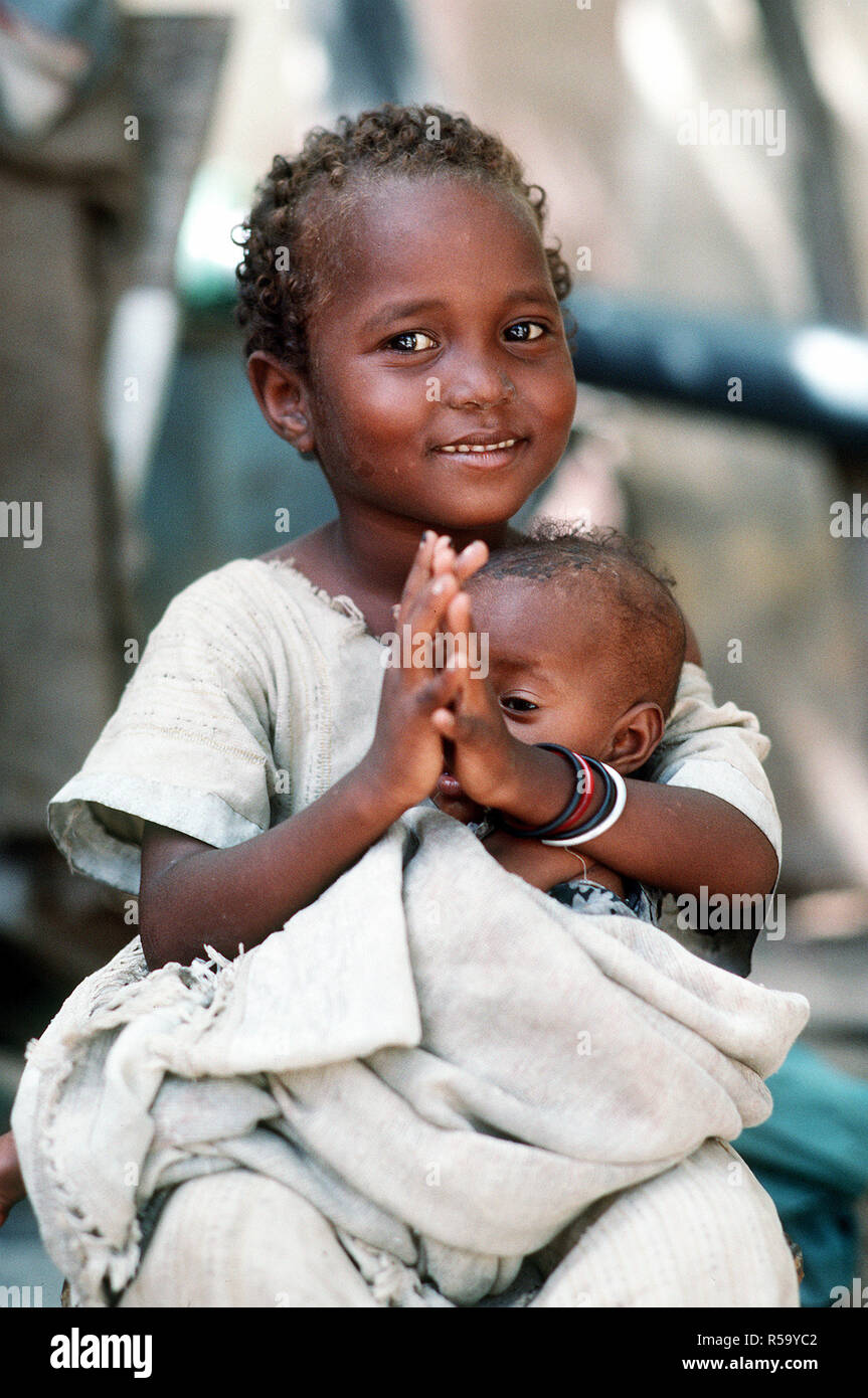 A Somali girl holding an infant waits to be examined by a Navy corpsman.  Combat Service Support Detachment 15 (CSSD-15) is conducting a medical civic action program during the multinational relief effort Operation Restore Hope. Stock Photo