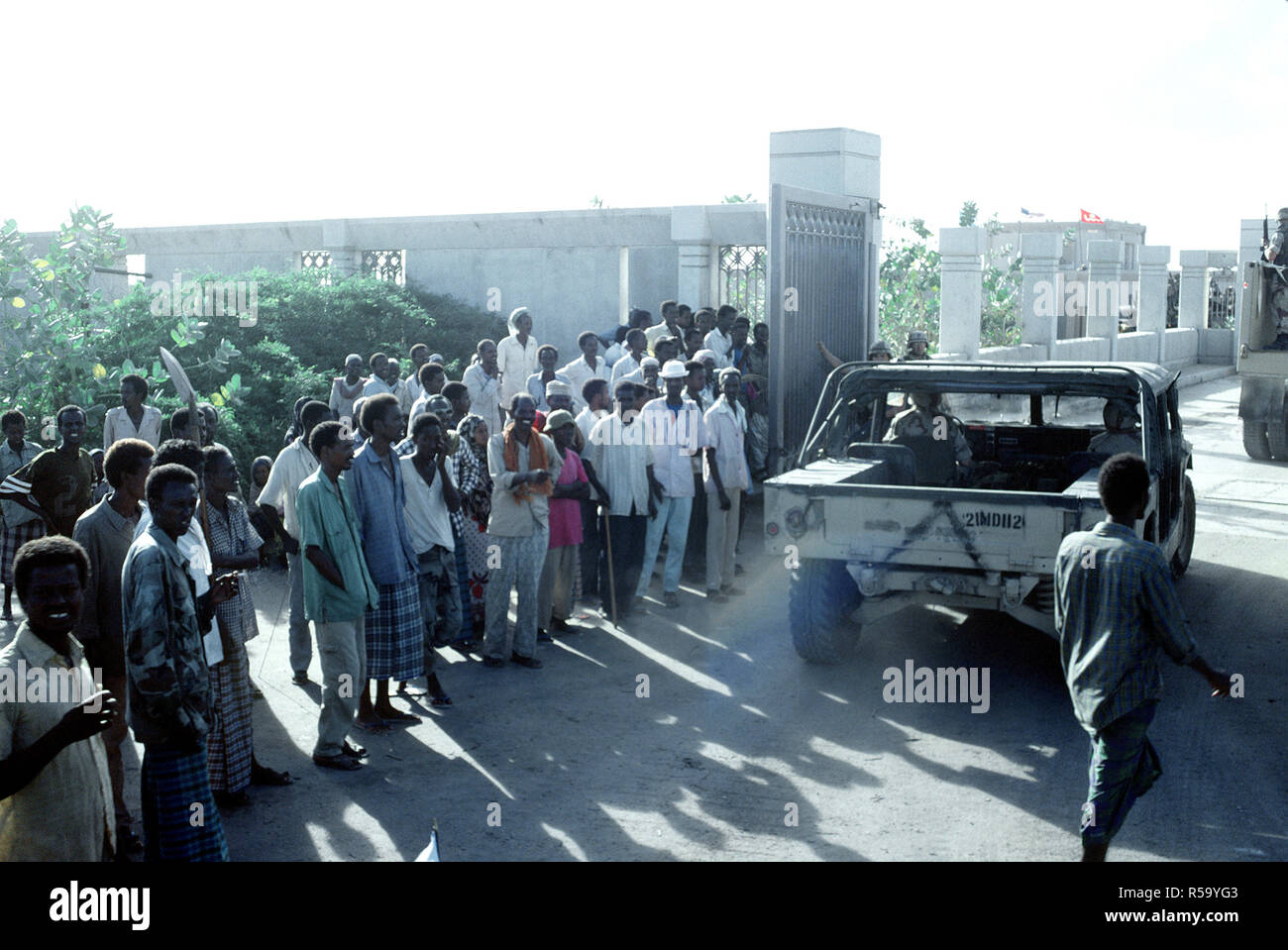 1992 - Somalis watch as an M-998 series vehicle enters the Joint Task Force Somalia headquarters.  The headquarters was established at the former U.S. Embassy compound during the multinational relief effort Operation Restore Hope. Stock Photo